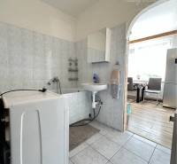 Washing machine in a bathroom with tiles and a wooden decor floor in a studio apartment.