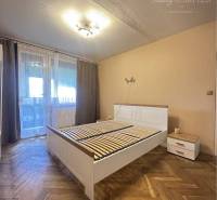 A bedroom in a one-room apartment with a bed and a wooden decor floor.