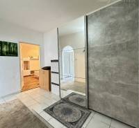 Entrance hall with tiled flooring, mirrored doors, view into a room with wood-patterned flooring.