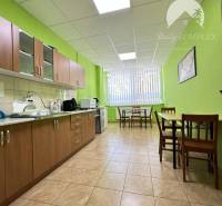 Offices with a kitchenette, wood-patterned flooring, light green walls, furniture, and dining area.