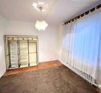 A room in a 3-room apartment with a carpet and a floor with a wooden decor.