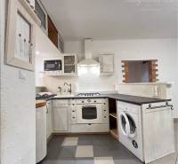 A kitchen in a 3-room apartment with a built-in oven and dishwasher, with ceramic tiles.