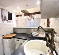 A kitchen unit with a brass faucet in a 3-room apartment with a wooden decor floor.