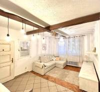 Living room with wood-patterned flooring in a 3-room apartment, white sofa and curtains.