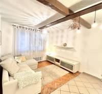 Living room in a three-room apartment with a wooden decor floor and a beamed ceiling.