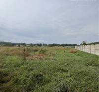 Residential plots in Iža with a view of the surrounding countryside and a fence.