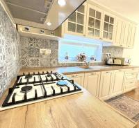 A kitchen in a family house with a wood-patterned floor and patterned tiles.