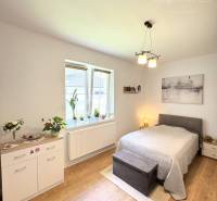 Bedroom in a family house with a bed, dresser, and wooden decor flooring.