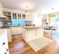 A kitchen with a dining area in a family house, wooden decor flooring, cream cabinets.