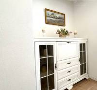 A room with a white dresser, wood-patterned flooring, and a painting on the wall in a family house.