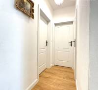 A hallway in a family house with wallpaper and a wooden decor floor.