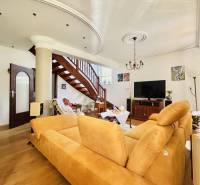 A family house with a wooden decor floor, staircase, sofa, and television.