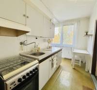 A kitchen in a 2-room apartment with a gas stove and a dining area.