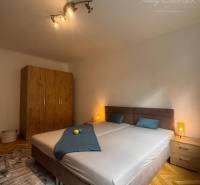 A bedroom in a one-room apartment with light, a wardrobe, and a bed on the floor with a wooden decor.
