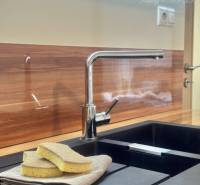 Kitchen sink with a black surface, floor with a wooden decor in a studio apartment.