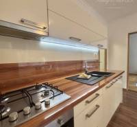 A kitchen unit in a one-room apartment with a wooden decor floor and a cooktop.