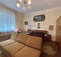 Living room in a family house with a sofa, chandelier, and light curtain on the window.