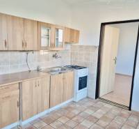 Kitchen in a studio apartment with tiled flooring and wooden decor cabinets.