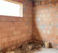 An unfinished room in a family house with brick walls and construction materials.