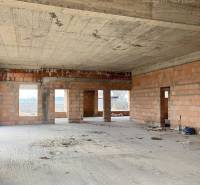 A spacious interior of an unfinished family house with visible bricks and a concrete ceiling.
