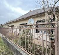A family house in Strekov behind a metal fence, surrounded by trees and a peaceful environment.