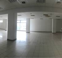Interior of commercial spaces with tiled flooring, white walls, and columns.