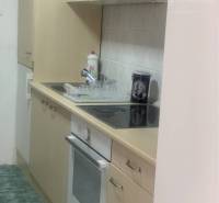 A kitchen with beige cabinets and white appliances in the space of warehouses and halls.