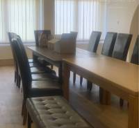 A room with a table and upholstered chairs, a floor with a wooden decor.