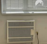 Radiator under the window with blinds in commercial premises.