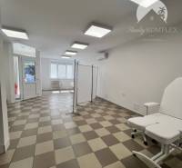 Interior of commercial spaces with tiles, a white sofa, and large windows.