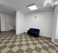 Commercial premises with tiled floor and sink, seating in the corner of the room.
