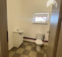 A toilet with a sink and a window in commercial premises with a simple design.