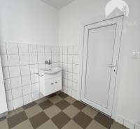 Commercial space with a checkered floor and white walls, featuring a door and a sink.