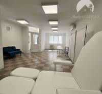 Commercial space with an armchair and a dark blue sofa on a white-brown floor.