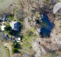Aerial view of a plot in Dedina Mládeže with a garden and a pond, ideal for living.