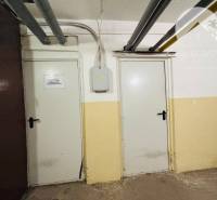 Two white doors in the basement of a 3-room apartment with pipes on the ceiling.