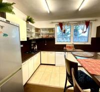 A kitchen in a family house with white furniture, a refrigerator, and a dining table.