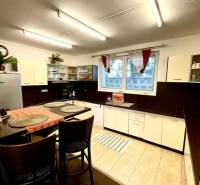 Interior of a family house with a kitchen, bar stools, and a wooden decor floor.