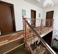 Interior of a family house with a brown carpet and metal railing on the staircase.