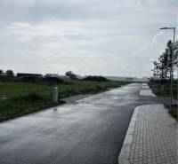 Asphalt road on Bučuháza in Šamorín, surrounded by plots designated for housing.