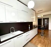 A kitchen in a 2-room apartment with white cabinets and a wood-patterned floor.
