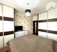 Bedroom in a 2-room apartment with wallpaper, TV, and a large wardrobe.