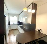 A kitchen in a two-room apartment with a wooden decor floor and a bar table.