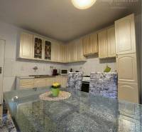 A kitchen with a glass table and beige cabinets in a family house.