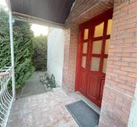 Entrance to a family house in Vrakúň with a covered veranda and a brick wall.