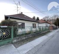 A family house in Vrakúňa with a colorful fence and a satellite dish. A street next to the house.
