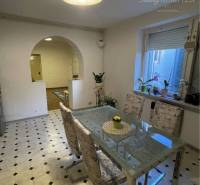 Dining room in a family house; glass table, chairs, window with plants on the windowsill.