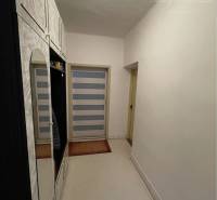 A narrow hallway with white furniture and spot lighting in a family house.