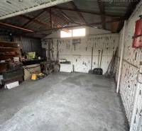A garage in a family house in Vrakúňa with a concrete floor and stored tools.