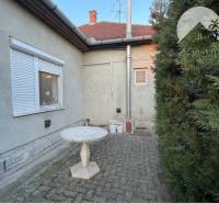 A family house in Vrakúň with a stone table on a paved terrace surrounded by greenery.